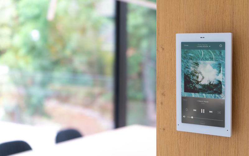 Wall-mounted touch panel controlling whole-home audio in a modern living space
