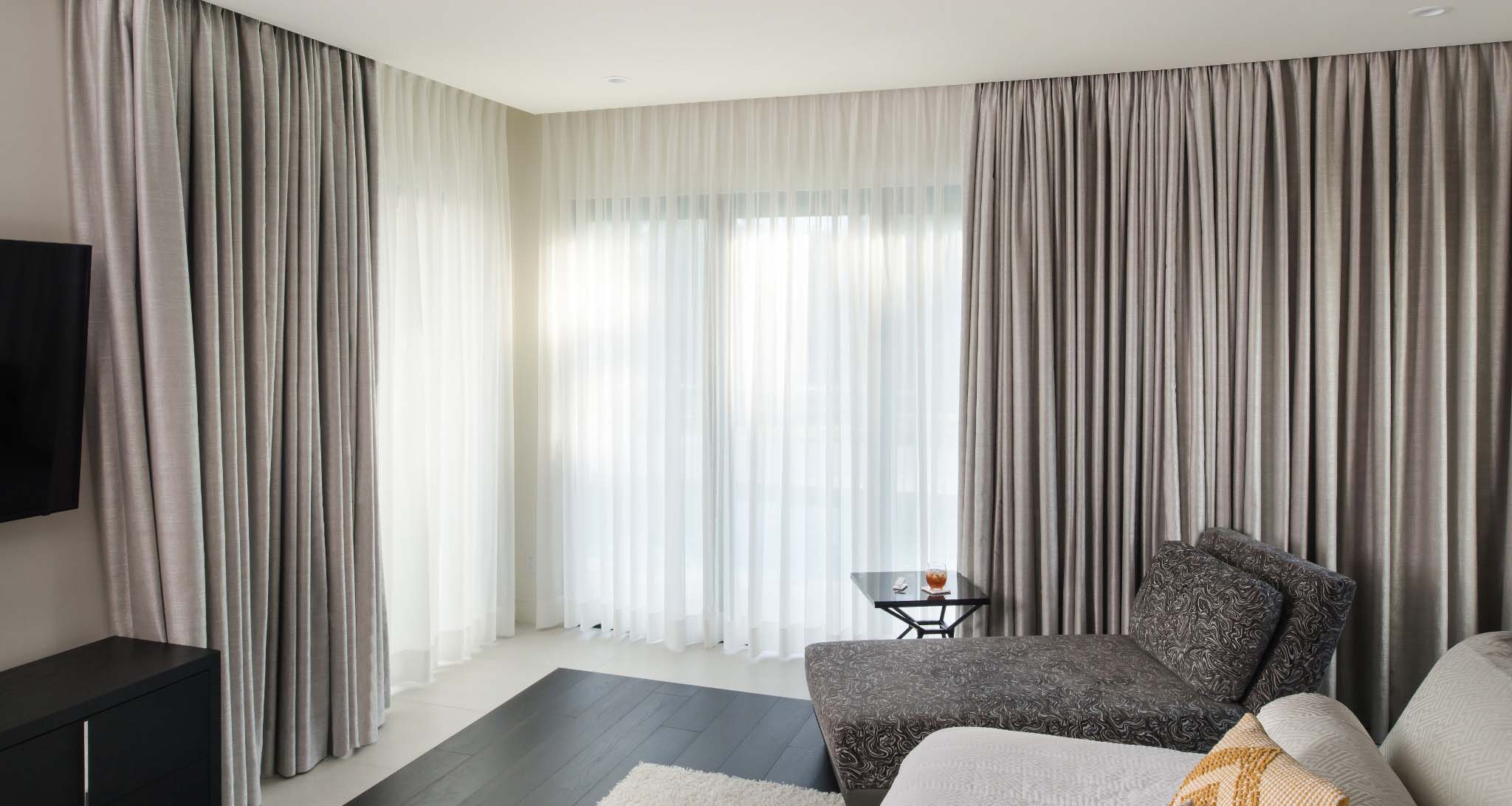 Elegant gray Lutron automated drapery partially covering large windows.