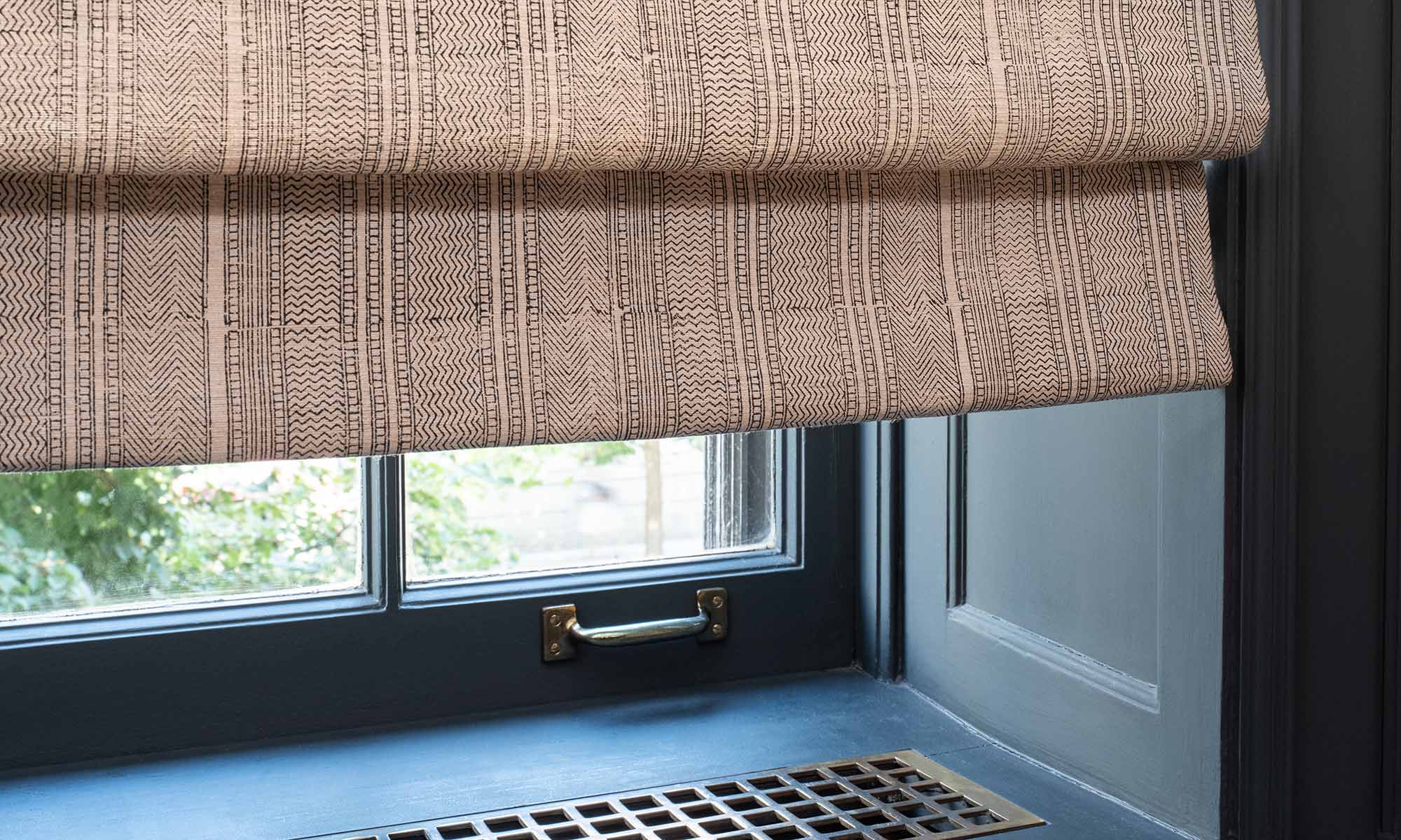Lutron Roman shades in patterned fabric over a dark blue window seat.
