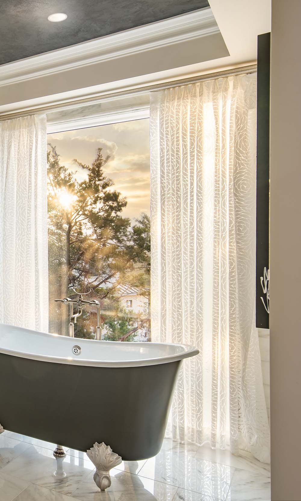 Sheer patterned Lutron drapery filtering sunlight in a luxury bathroom.