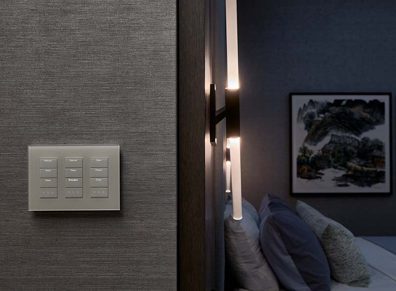 Gray Lutron Palladiom keypad mounted on a dark textured bedroom wall.