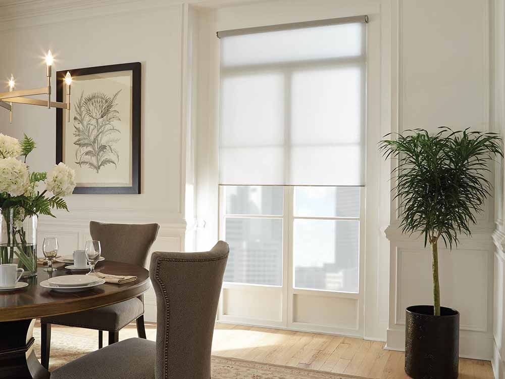 Dining room featuring sheer white Lutron Palladiom roller shades.