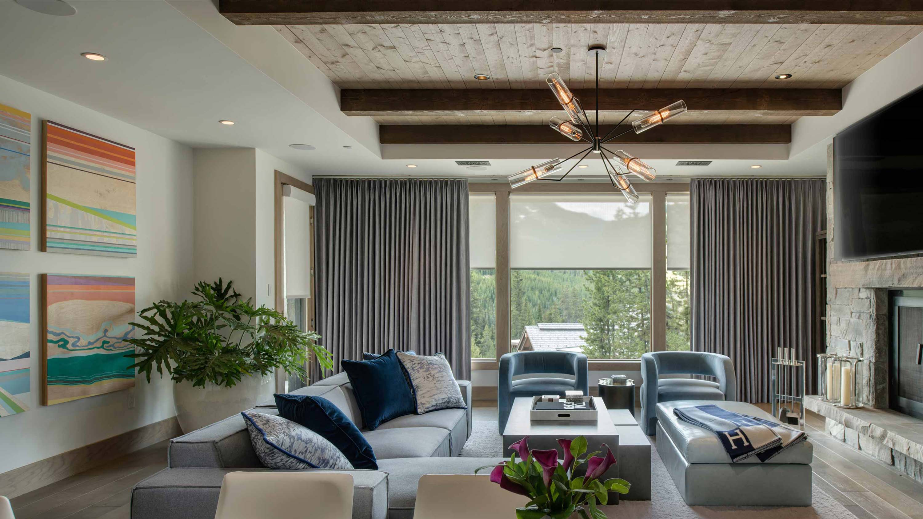 Living room featuring gray Lutron drapery and sheer roller shades.