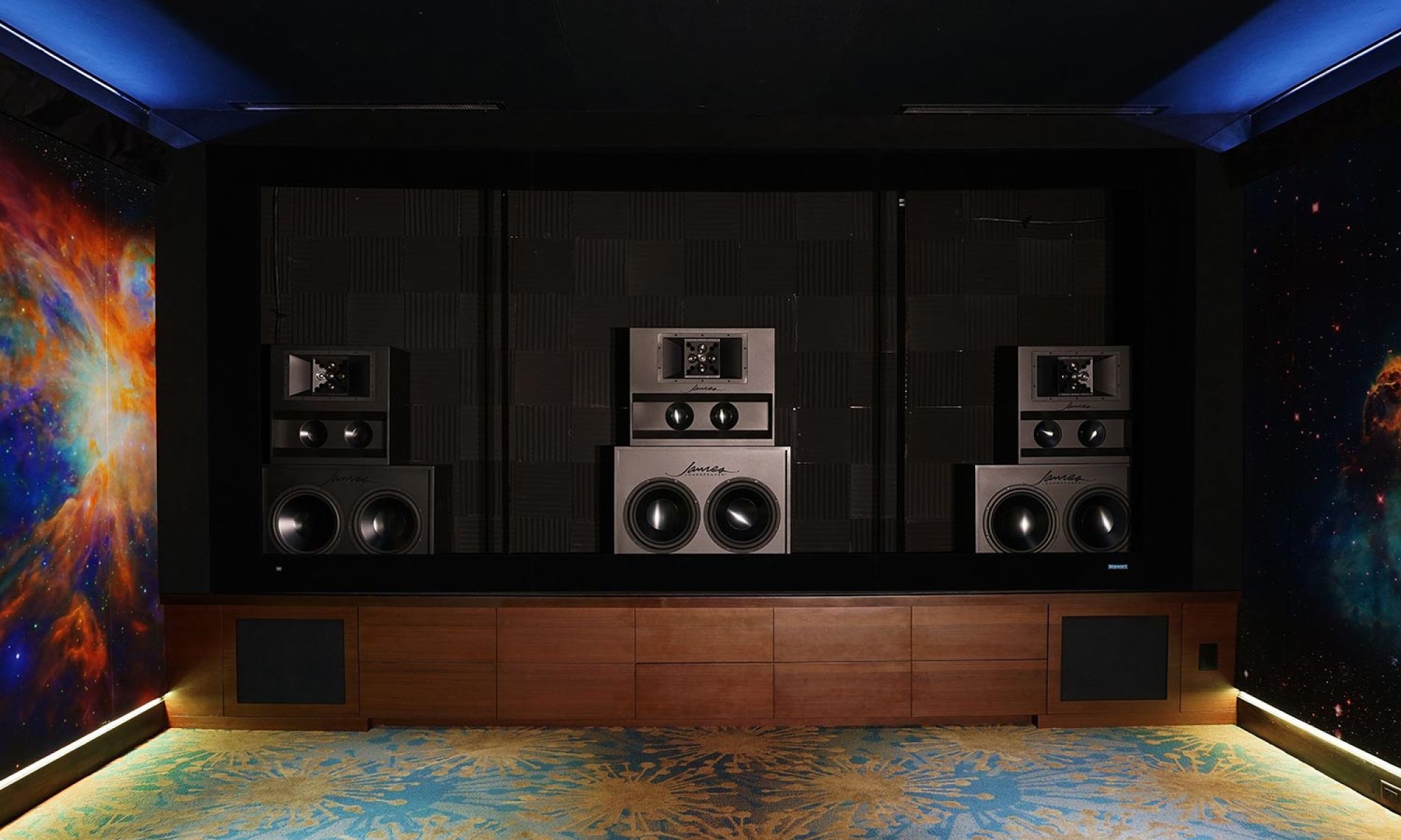 Three large high-end speaker stacks integrated into a dark home theater wall