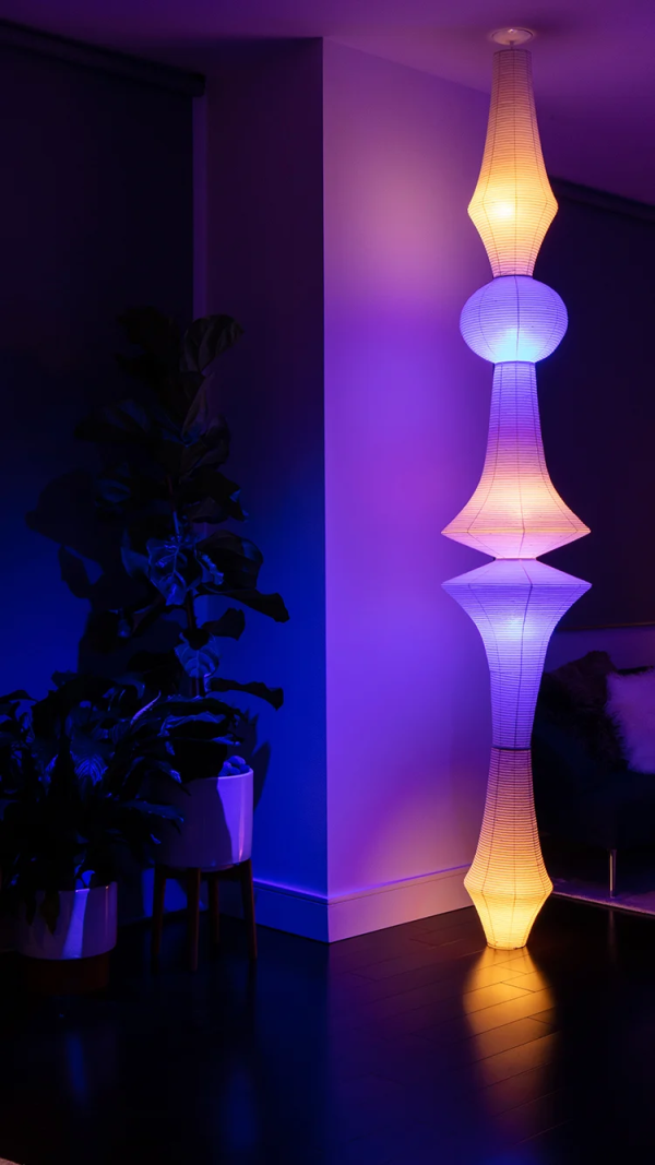 A modern floor lamp illuminated at night with warm and purple lighting.